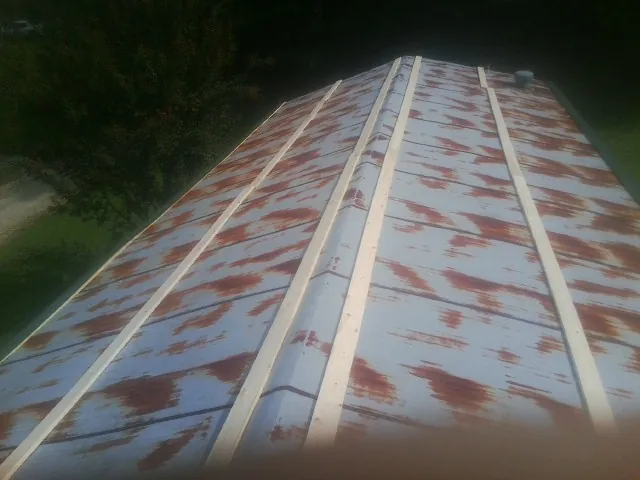 Rusted metal roof panels with new wood purlins before replacement — Storm Damage Roof Repair in King Hill by Roofing Brothers