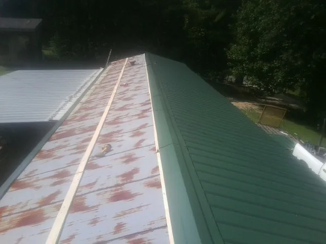 Old rusted panels beside newly installed green metal roofing — Wind Damage Roof Repair by Roofing Brothers in King Hill