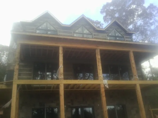Dormers and porch framing on a large log home under construction — Roof Coating work by our crew in King Hill