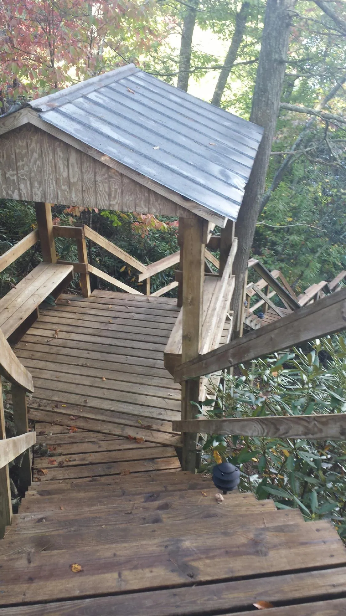 Metal roofed shelter over wooden steps on a wooded walkway — Skylight Repair & Installation work by our crew in King Hill
