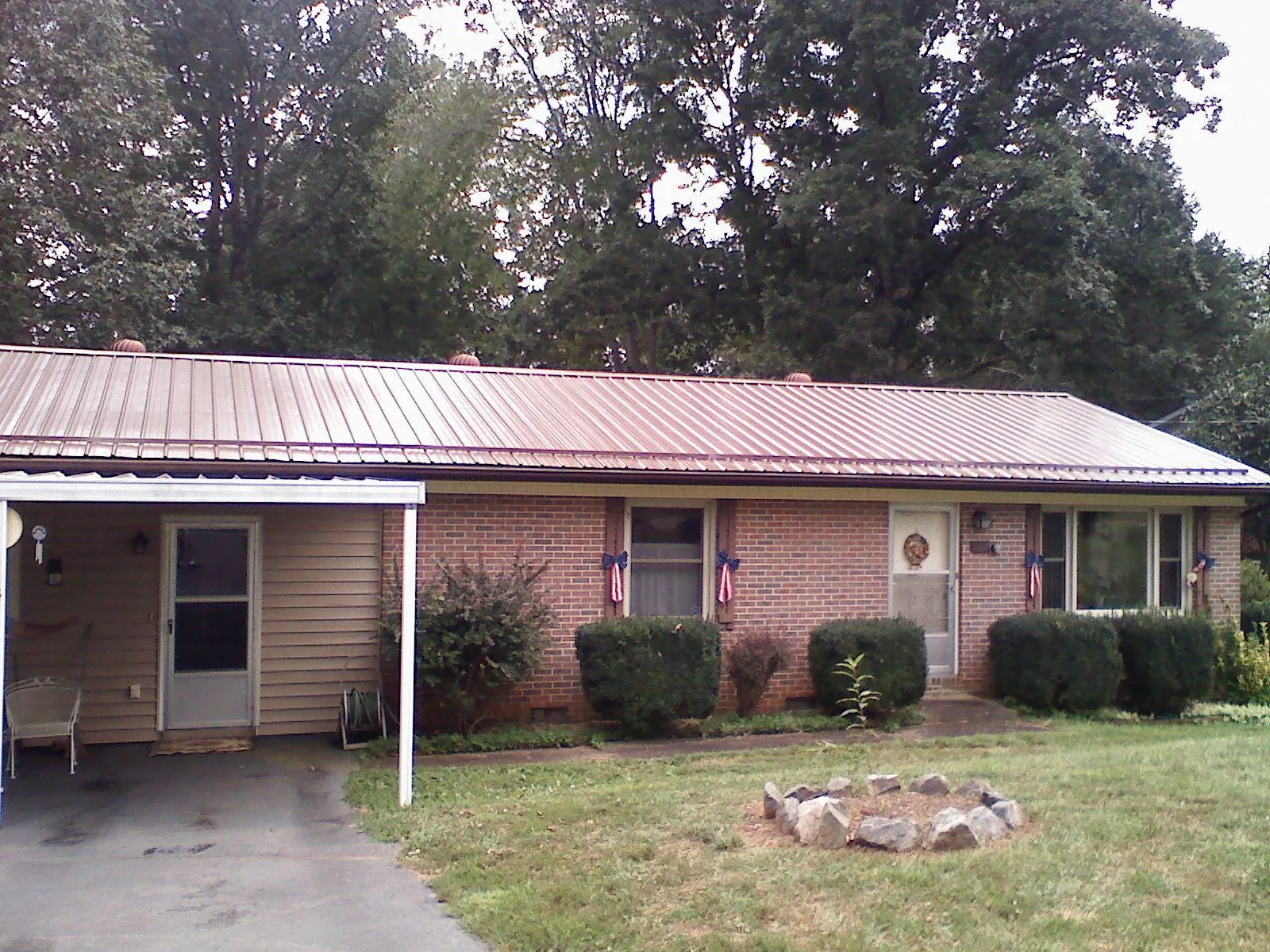 Bronze metal roof and carport on a brick ranch home — Roof Repair work by our crew in King Hill